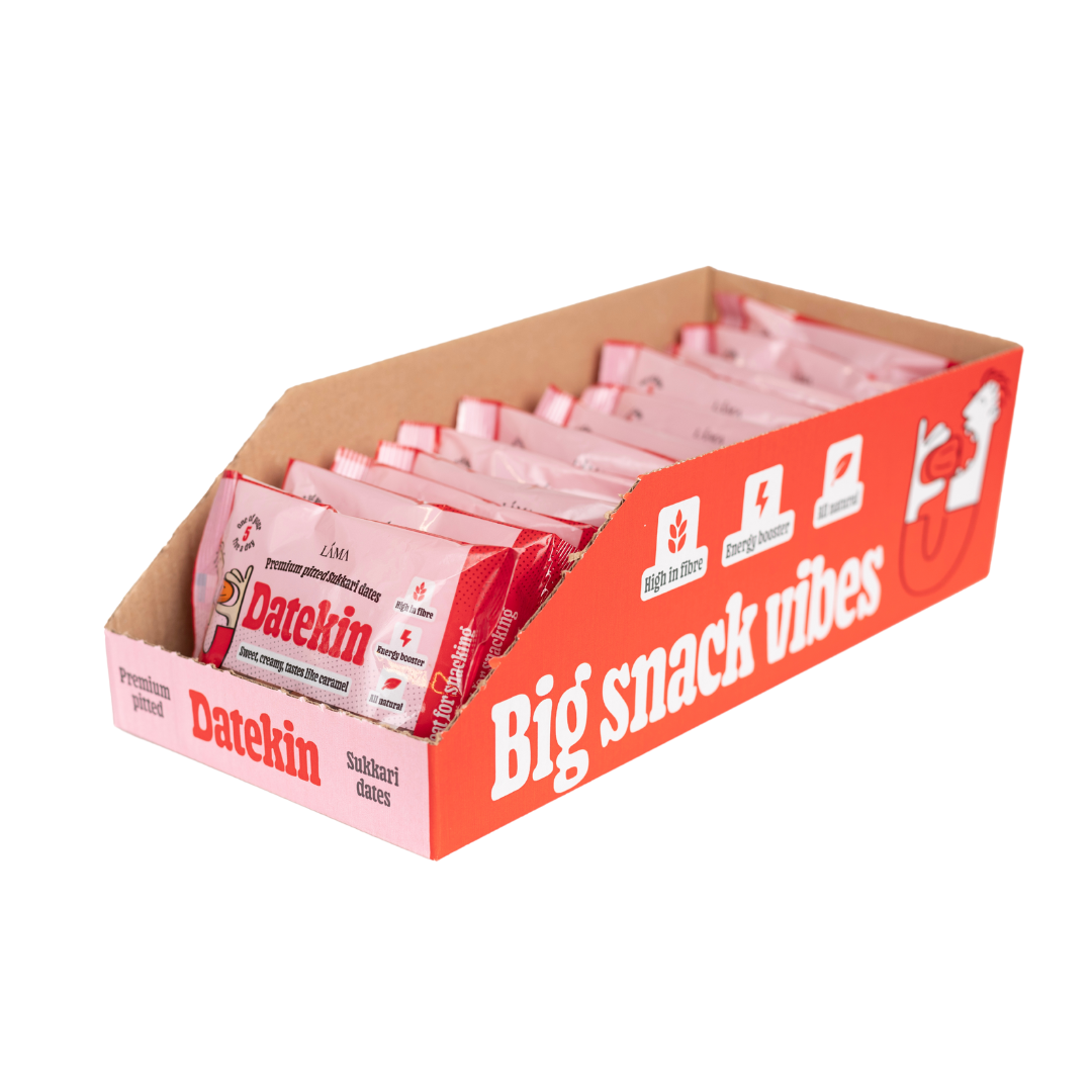 A display box of pink-wrapped Datekin Premium Pitted Sukkari Dates offers a healthy snack experience with the slogan Big snack vibes, highlighting benefits like energy boosting, natural ingredients, and sweetness from pitted Sukkari dates.